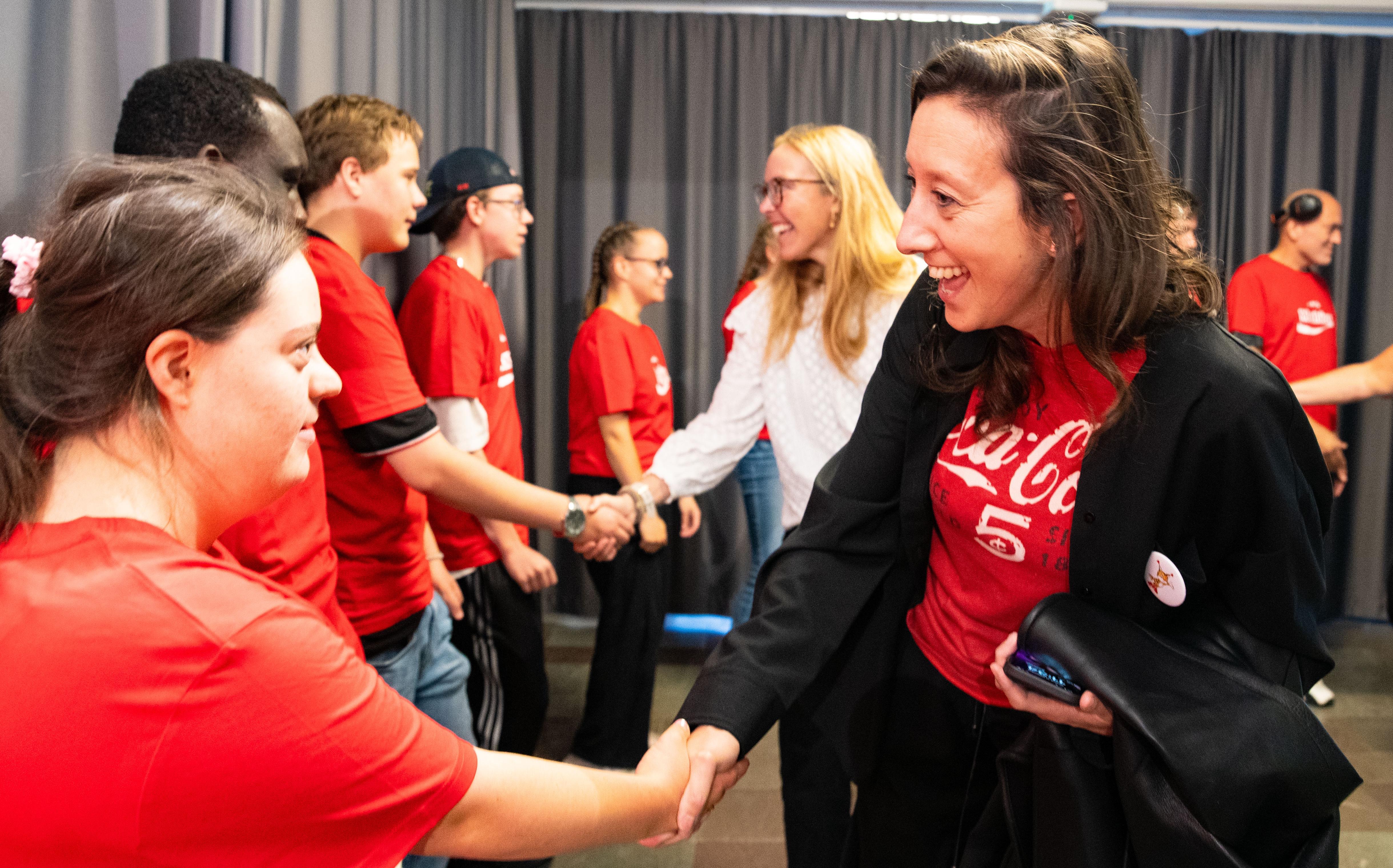 Foto, inomhus. Två personer ta en selfie med en Special Olympics-idrottare framför en sponsorvägg.
