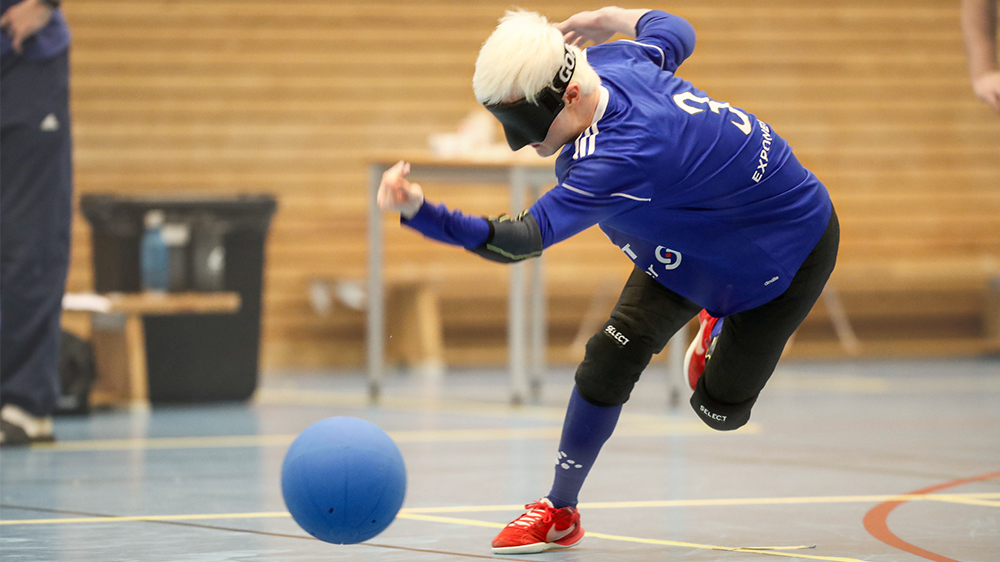 En spelare i blå tröja och ögonbindel kastar iväg den blå bollen.